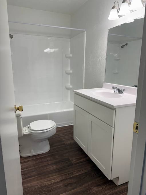 A white bathroom with a toilet, sink, and mirror.