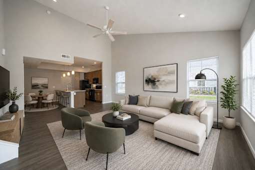 A living room with a white couch, a grey armchair, a coffee table, and a ceiling fan.