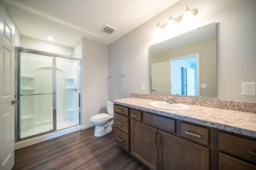 A bathroom with a toilet, sink, and mirror.