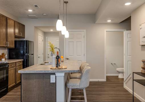 A kitchen with a black refrigerator and wooden cabinets.
