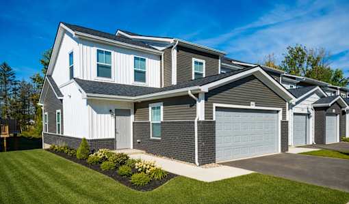 A modern house with a white and grey exterior and a well-maintained lawn.