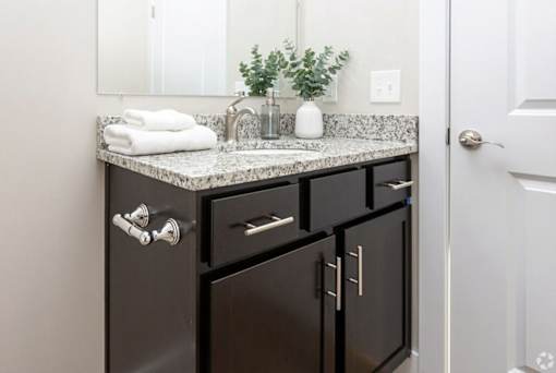 A bathroom with a sink, mirror, and cabinets.
