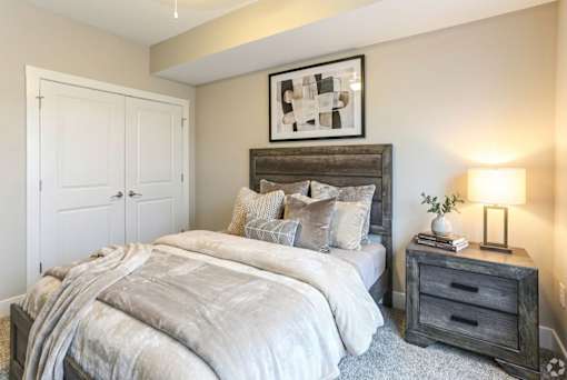 A bedroom with a large bed and a wooden nightstand.