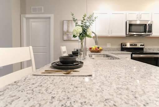 A kitchen with granite countertops and a white chair.