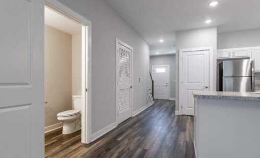 A modern kitchen with a wooden floor and white walls.