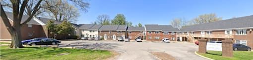A sunny day at a residential complex with cars parked in the driveway.