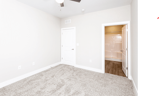 A room with a carpeted floor and a ceiling fan.