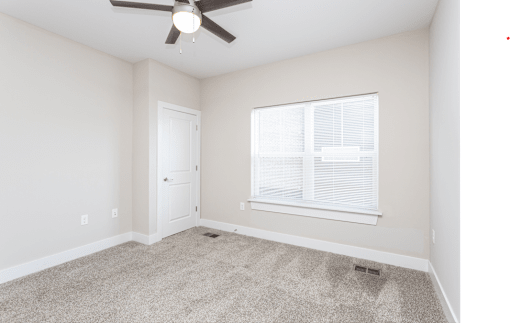A room with a ceiling fan and a window with blinds.