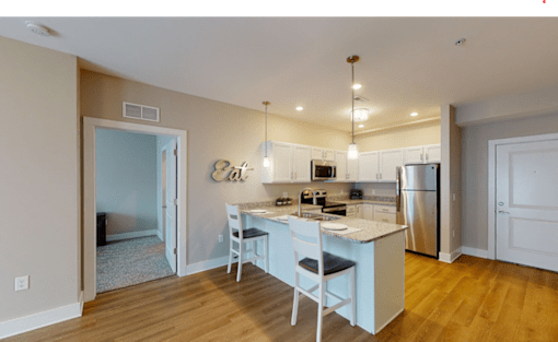 A kitchen with a table and chairs in front of it.