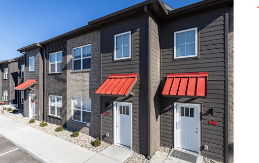 A row of houses with red awnings on the front.
