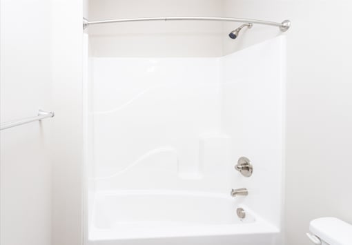 A white bathtub with a shower head and faucet.
