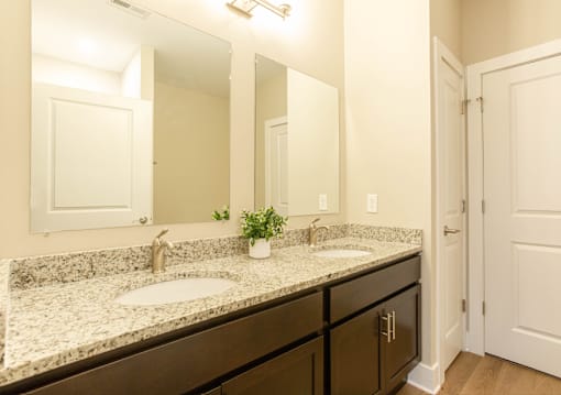 A bathroom with a granite countertop and a double sink.