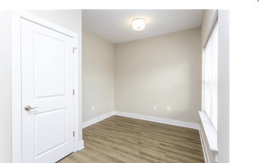 A room with a white door and wooden flooring.