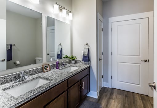 A bathroom with a white door and a mirror above the sink.