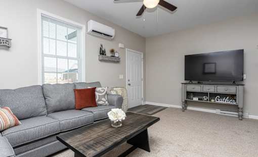 A living room with a grey couch, a wooden coffee table, and a flat screen TV.