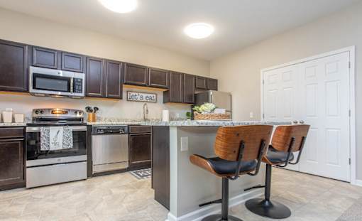 A kitchen with a counter and chairs.
