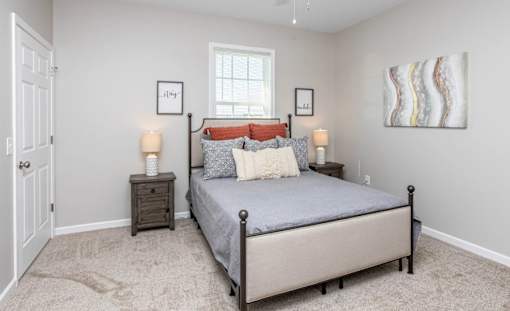A bedroom with a bed, nightstands, and a painting on the wall.