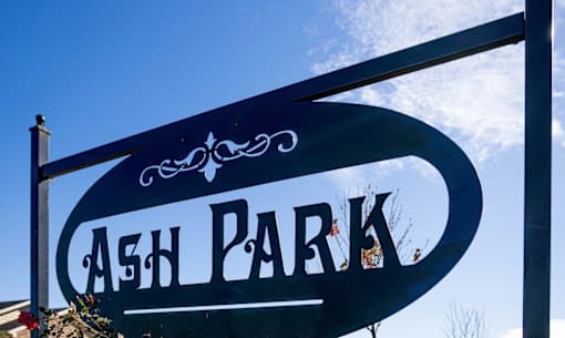 A sign that says Ash Park is shown in front of a blue sky.