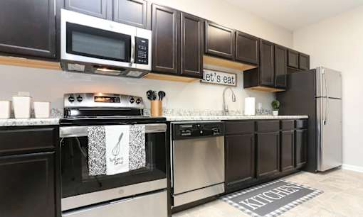 A kitchen with dark brown cabinets and stainless steel appliances.