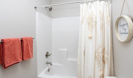 A white bathroom with a shower curtain and a towel rack.