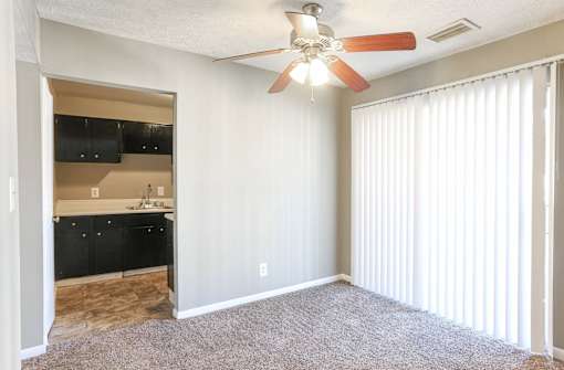 A room with a ceiling fan and a window with blinds.
