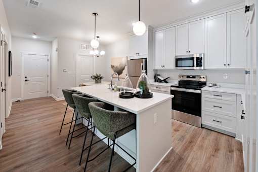 A kitchen with a white island and chairs.