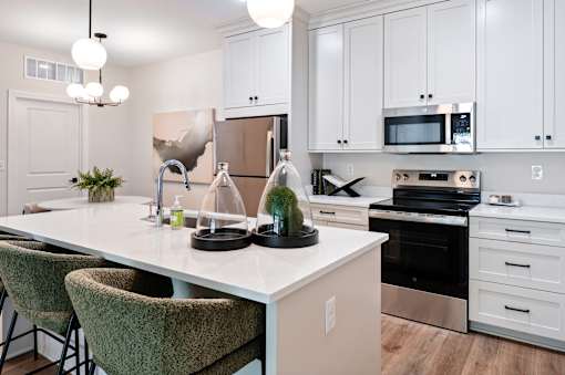 A kitchen with white cabinets and a large island with a sink and a potted plant on it.