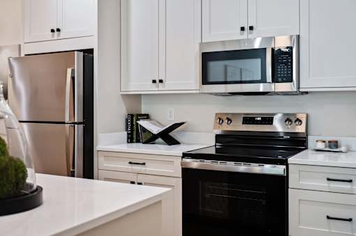 A modern kitchen with a black oven and white cabinets.