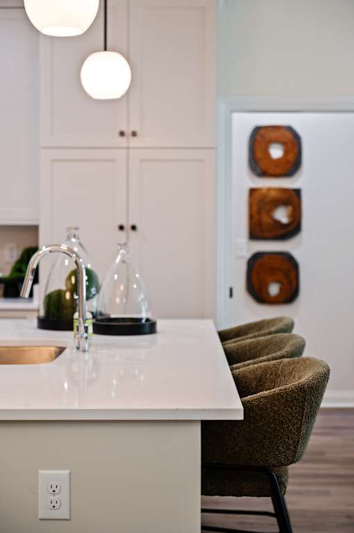 A kitchen with a white counter and brown chairs.