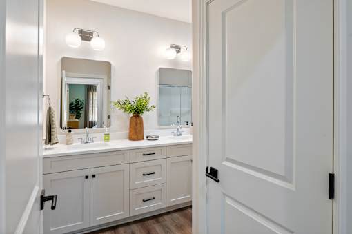 A bathroom with a white vanity and a mirror above it.