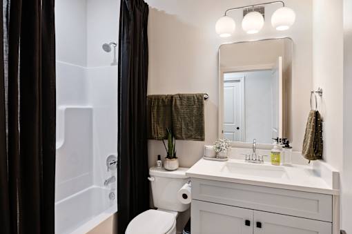 A white bathroom with a toilet, sink, and a mirror.