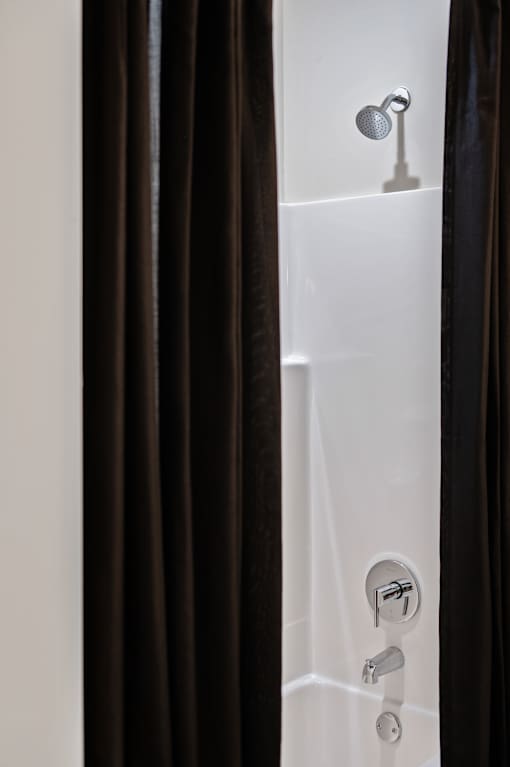 A white bathtub with a shower head and faucet.