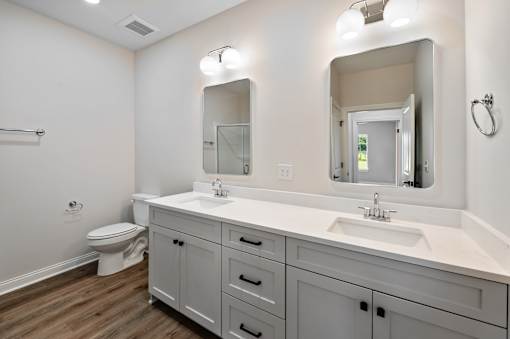 A white bathroom with a toilet, sink, and mirror.