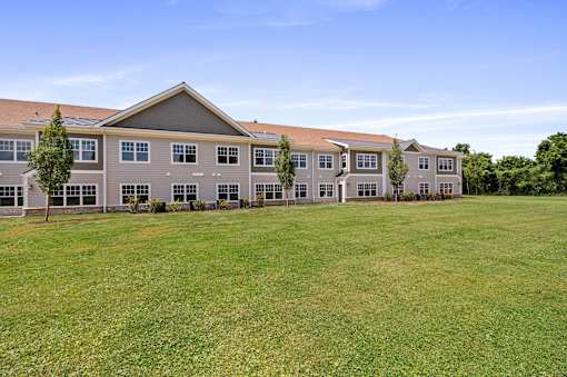 A large grassy field in front of a building with a brown roof.