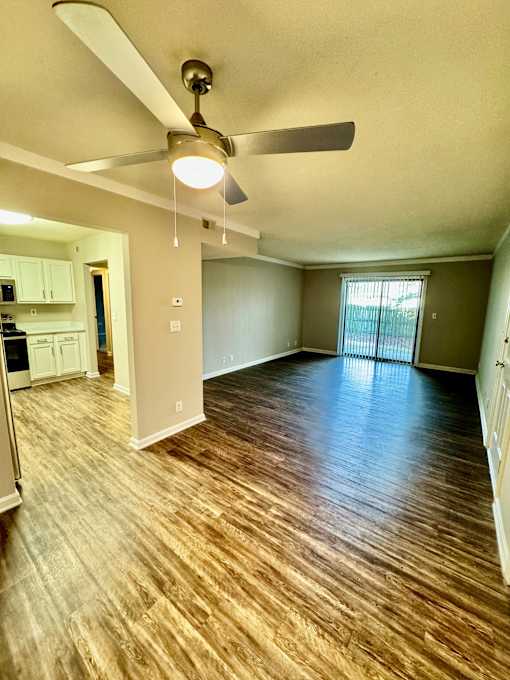 A room with a ceiling fan and wooden flooring.