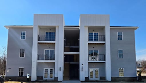 A modern two-story apartment building with balconies on the second floor.