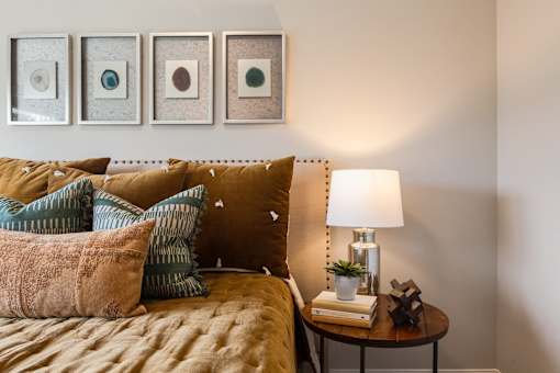 A bedroom with a bed, a lamp, and three picture frames on the wall.