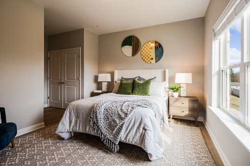 A bedroom with a bed, nightstand, and two wall lamps.
