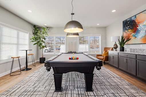 A pool table is in the middle of a room with a light hanging from the ceiling.