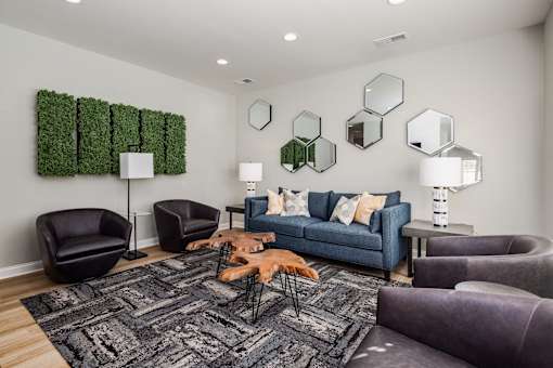 A living room with a grey rug and a blue couch.