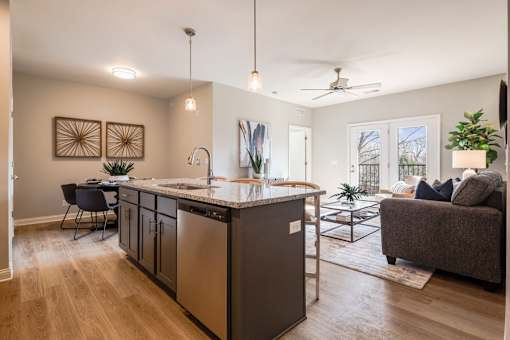 A modern kitchen with a large island and a dining area with a table and chairs.
