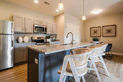 A kitchen with a granite countertop and white chairs.