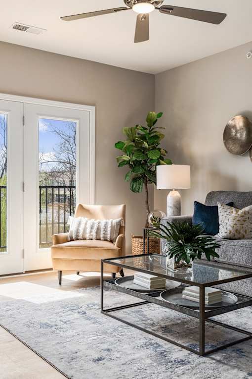 A living room with a glass coffee table and a sofa with a throw pillow.