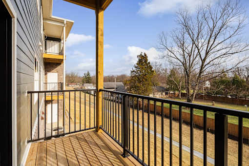 A balcony with a black railing and a wooden floor.