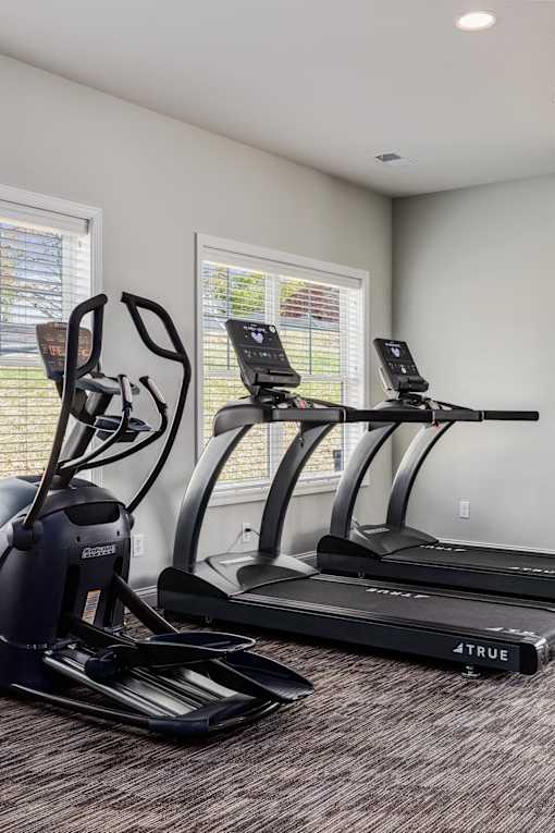 A room with a treadmill and a stationary bike.