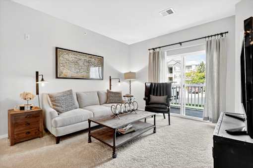 A living room with a grey couch, a coffee table, and a painting on the wall.