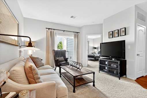 A living room with a white couch and a black television.