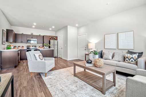 A modern kitchen with a breakfast bar and a living room with a grey couch.