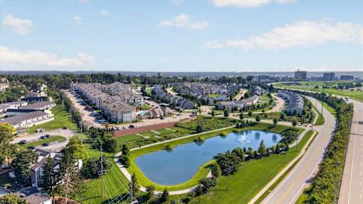 A suburban neighborhood with a pond and a road running through it.