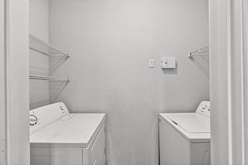 A laundry room with two washing machines and a shelf.